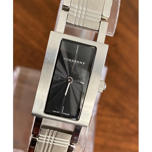 384 - A ladies Burberry fashion watch with Swiss quartz movement. Black rectangular dial with applied bato... 