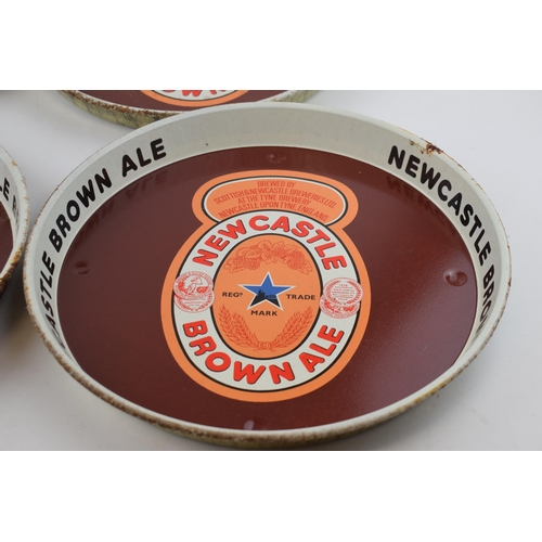 300 - Four tin Newcastle Brown Ale advertising pub trays. Three of the same design with brown ground and a... 