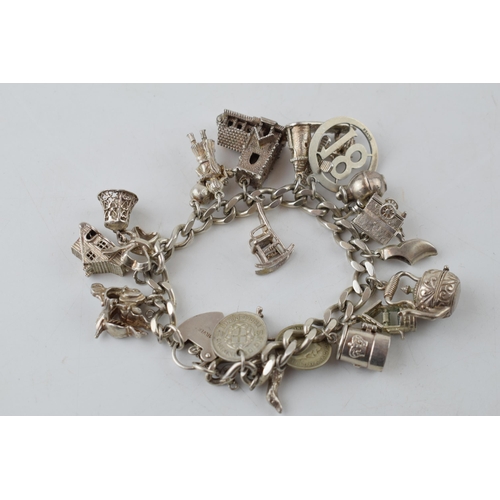 389 - Silver charm bracelet with charms to include a windmill, a bell, a teapot and others, 81.6 grams.