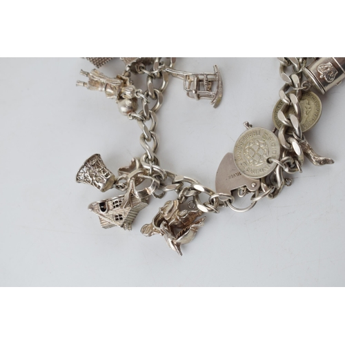 389 - Silver charm bracelet with charms to include a windmill, a bell, a teapot and others, 81.6 grams.