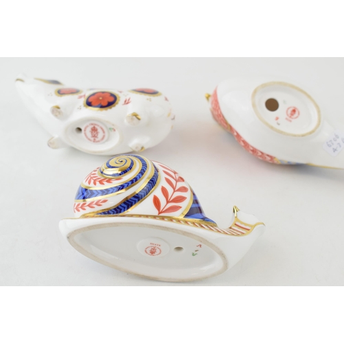 22 - Royal Crown Derby paperweights in the form of an imari pig, a garden snail, both ceramic stoppers an... 