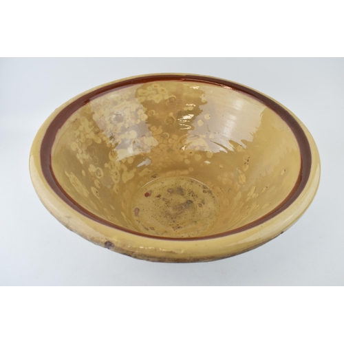 287 - An antique English dairy bowl with cream / brown salt glaze. Diameter 40cm. Height 19cm.