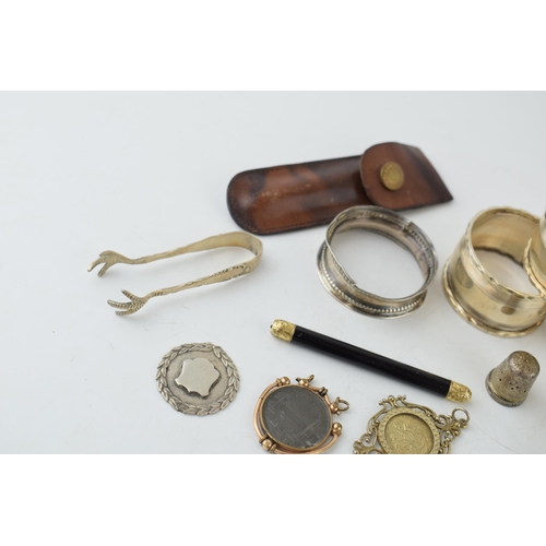 321 - A collection of silver items to include napkin rings, thimble, fob and sugar nips (approx 90 grams) ... 