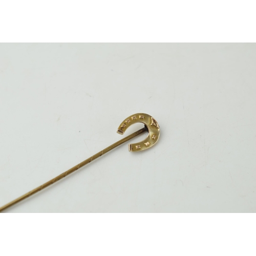 356 - 9ct gold stick pin in the form of a horse's shoe, on base metal pin, 1.3 grams, 72mm long.