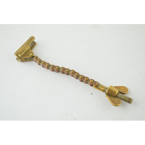 559 - Antique brass novelty bottle top remover, tension and screw type movement, 14cm long.