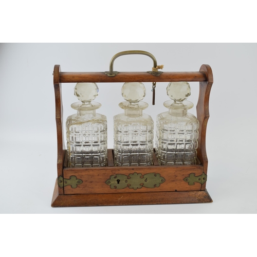 615 - Tantalus in golden oak with brass fittings. Containing three glass decanters, with original key. Hei... 