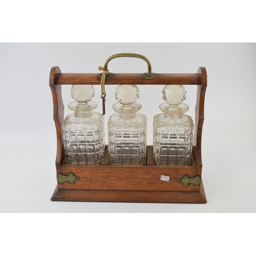 615 - Tantalus in golden oak with brass fittings. Containing three glass decanters, with original key. Hei... 