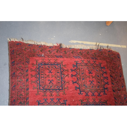 580 - A hand-knotted oriental / middle-eastern carpet in deep reds, blue and blacks. 93cm x 190cm.