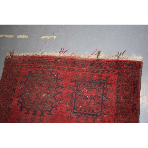 580 - A hand-knotted oriental / middle-eastern carpet in deep reds, blue and blacks. 93cm x 190cm.