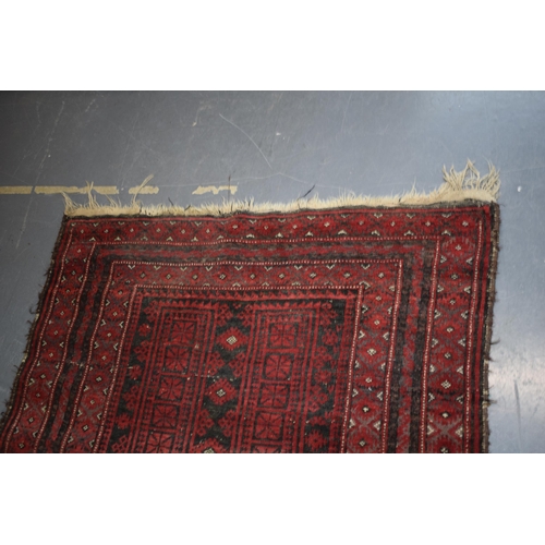 582 - A hand-knotted oriental / middle-eastern carpet / rug in deep reds, blue and blacks. 111cm x 205cm.