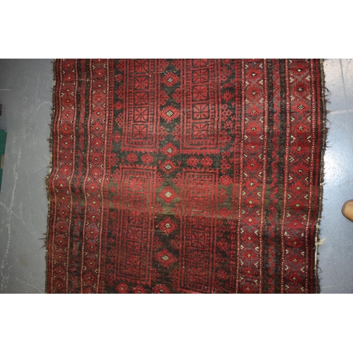 582 - A hand-knotted oriental / middle-eastern carpet / rug in deep reds, blue and blacks. 111cm x 205cm.