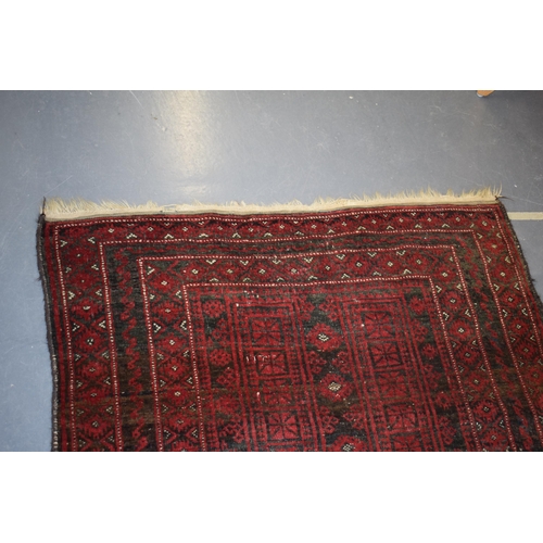 582 - A hand-knotted oriental / middle-eastern carpet / rug in deep reds, blue and blacks. 111cm x 205cm.