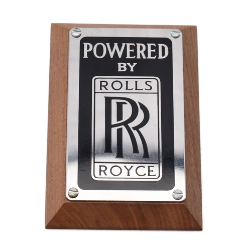 139 - An original 'Rolls-Royce' (Powered By) badge mounted on factory American black walnut. 15cm x 10cm x... 