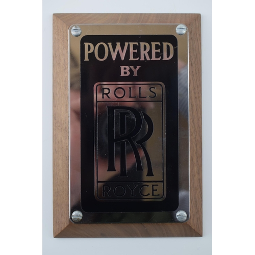 139 - An original 'Rolls-Royce' (Powered By) badge mounted on factory American black walnut. 15cm x 10cm x... 