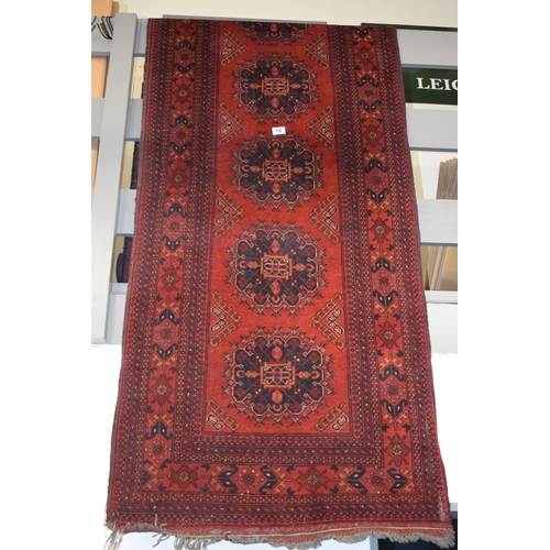 76 - A oriental / middle-eastern runner carpet / rug in deep reds, blues, oranges and cream. 83cm x 390cm... 