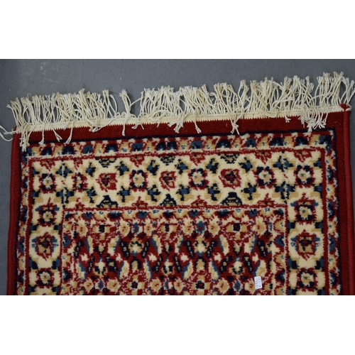 183 - A Persian style hearth rug in red blues and creams. 59cm x 108cm.