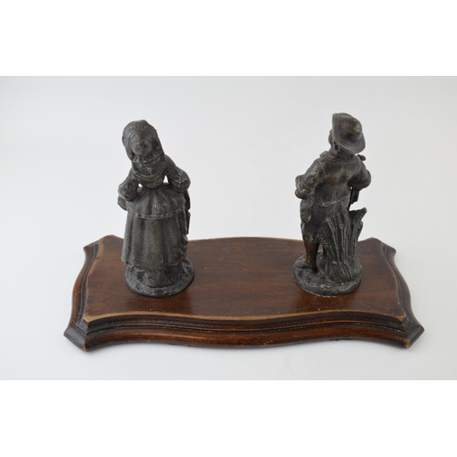 202 - Two spelter figures mounted on a wooden base. Height 19cm.