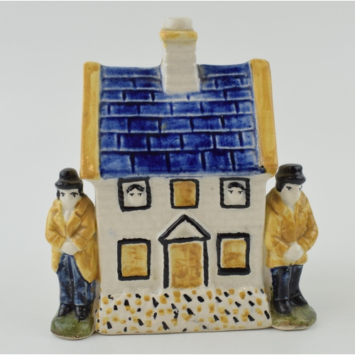 110A - Prattware money box in the form of a house with two figures either side. Height 12.5cm.