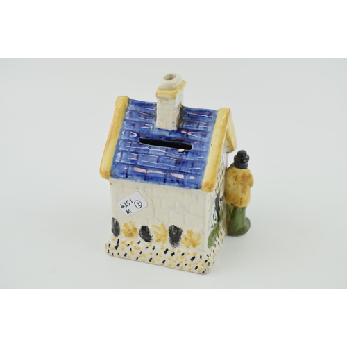 110A - Prattware money box in the form of a house with two figures either side. Height 12.5cm.