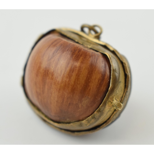 313 - A miniature purse made form a hazelnut shell with brass hinge and mount. 2.5cm.