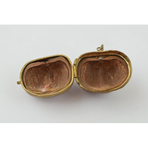 313 - A miniature purse made form a hazelnut shell with brass hinge and mount. 2.5cm.