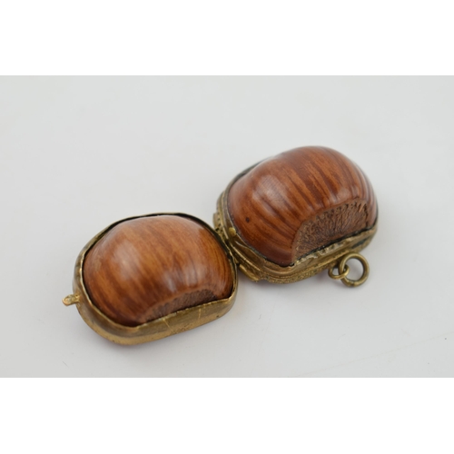 313 - A miniature purse made form a hazelnut shell with brass hinge and mount. 2.5cm.