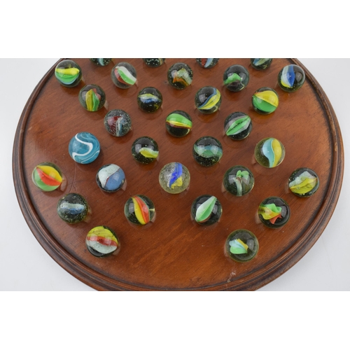 357 - An antique solitaire board with associated marbles. Diameter 30cm.