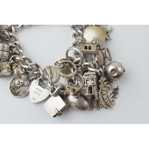 297A - Heavy silver charm bracelet to include an American football, a fish, a boat, a teapot and others, 11... 