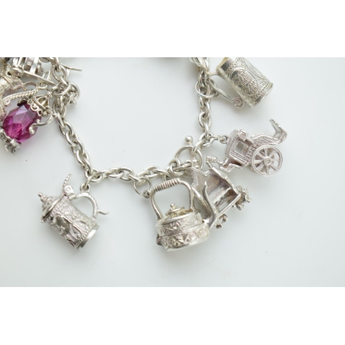 297B - Silver charm bracelet with  a teapot, a tankard, a cello, a throne and others, 65.0 grams.