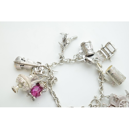 297B - Silver charm bracelet with  a teapot, a tankard, a cello, a throne and others, 65.0 grams.