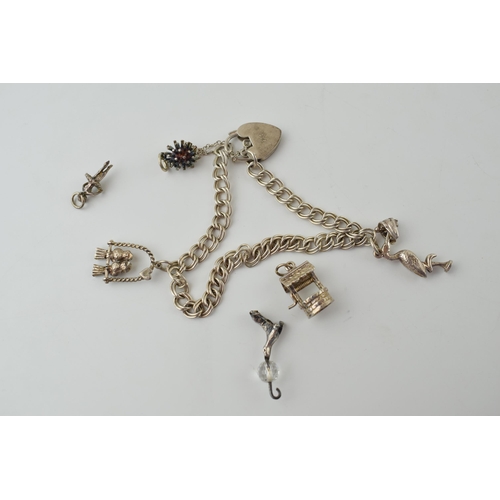 569 - A silver charm bracelet with two charms and padlock together with another four loose charms. 17.2 gr... 