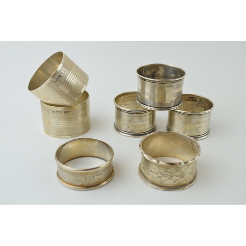 602 - A collection of silver napkin rings of varying forms / designs, to include 2 pair and 3 singular rin... 