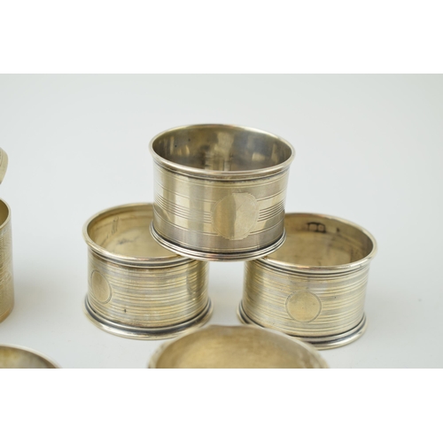 602 - A collection of silver napkin rings of varying forms / designs, to include 2 pair and 3 singular rin... 