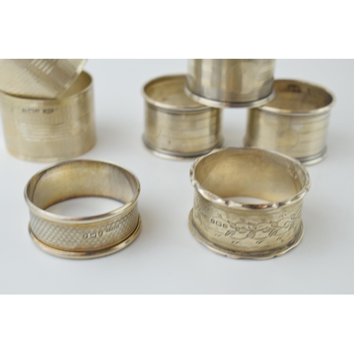 602 - A collection of silver napkin rings of varying forms / designs, to include 2 pair and 3 singular rin... 