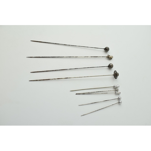 608 - A collection of hatpins to include two ornate silver examples and other white metal examples (9).