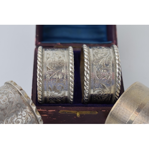 642 - A cased set of silver napkin rings together with two silver napkin rings. 119.5 grams.