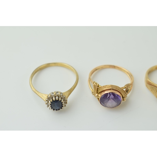 534 - A trio of 9ct gold rings to include a sapphire and illusion set diamond floral ring, an amethyst exa... 