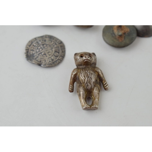 652 - A collection of metal detecting finds to include a silver teddy charm, a hammered silver coin, middl... 