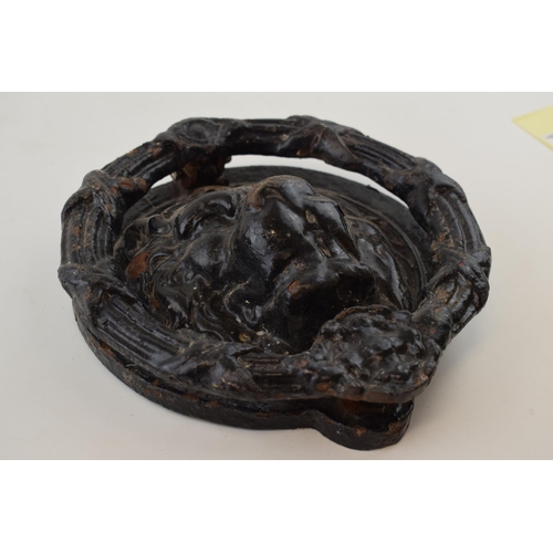 352 - A cast iron door knocker in the form of a lions head. 22cm diameter.