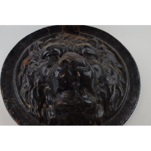 352 - A cast iron door knocker in the form of a lions head. 22cm diameter.