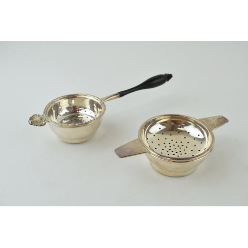 585 - Two silver tea strainers, 1 with a turned ebonised handle, London 1984, 17.5cm long, with a similar ... 