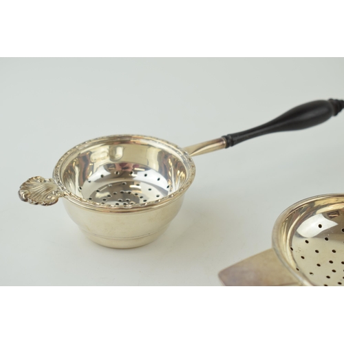 585 - Two silver tea strainers, 1 with a turned ebonised handle, London 1984, 17.5cm long, with a similar ... 