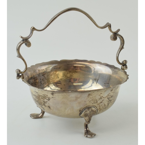 587 - Silver basket with ornate handle, raised on three feet, Sheffield 1945, 212.9g, 13cm wide.