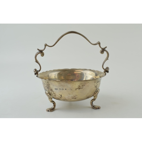 587 - Silver basket with ornate handle, raised on three feet, Sheffield 1945, 212.9g, 13cm wide.