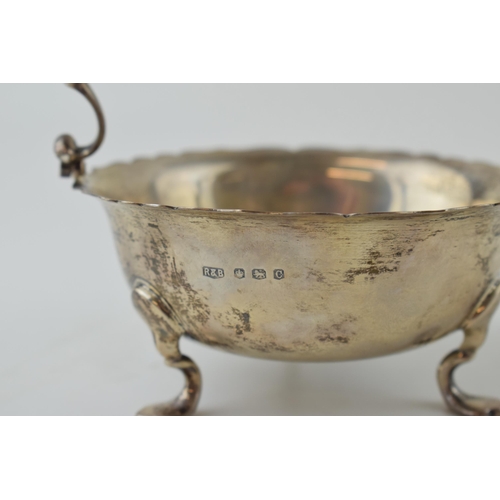 587 - Silver basket with ornate handle, raised on three feet, Sheffield 1945, 212.9g, 13cm wide.