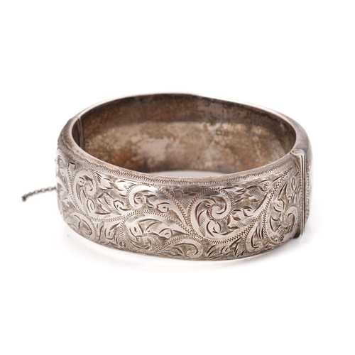 340 - Vintage silver bangle with hand chased repeated design and safety chain. Weight 42.6 grams.