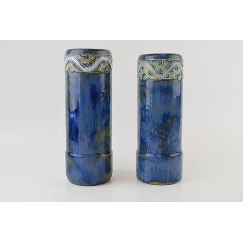 179 - A near pair of Royal Doulton stoneware cylindrical vases, with tubelined decoration to the tops, on ... 