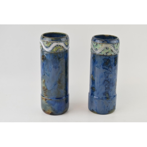 179 - A near pair of Royal Doulton stoneware cylindrical vases, with tubelined decoration to the tops, on ... 