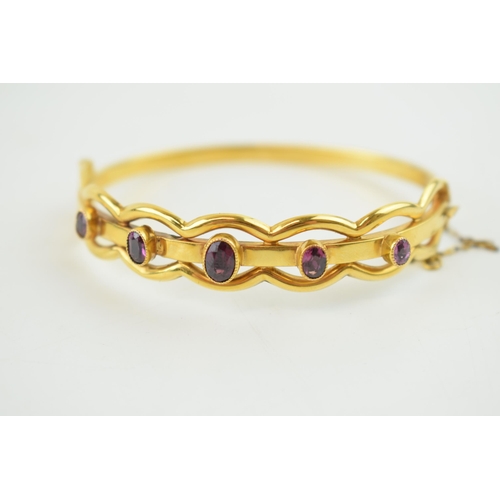 242 - Cased yellow metal (tests as 9ct gold or higher) bangle, set graduated Amethyst stones with safety c... 