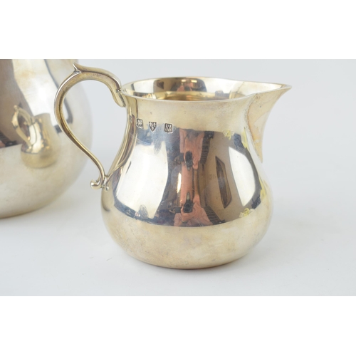 279 - A near graduated pair of silver bulbous jugs, the larger being London 1964, Edward Barnard & Sons, 2... 